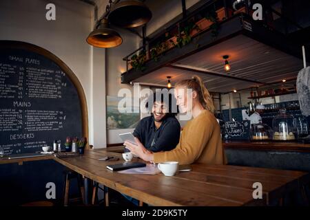 Happy young couple sitting and relaxing in cafe using digital tablet to watch videos Stock Photo