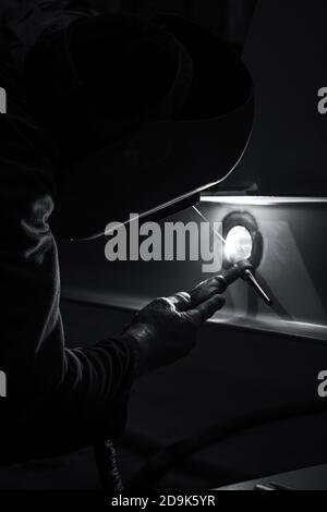Vertical grayscale shot of a welder working Stock Photo