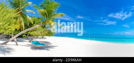 Tropical beach panorama as summer landscape with beach swing or hammock and white sand and calm sea for beach banner. Perfect beach scene vacation Stock Photo