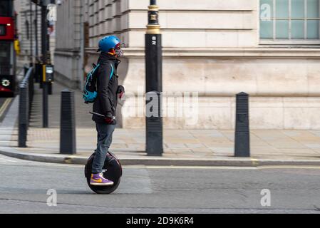 Electric unicycle rider in Whitehall, London, UK. Self balancing, one wheel personal transport rider riding on the road, wearing face mask and helmet Stock Photo