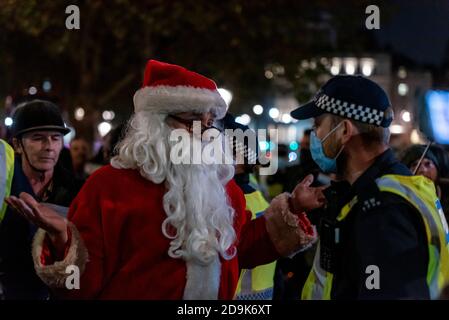 Anti lockdown protester dressed as Father Christmas remonstrating with a police officer wearing a face mask on first day of second COVID-19 lockdown Stock Photo