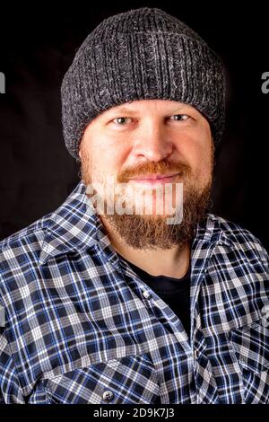 Solid bearded man in a wool cap portrait on black background Stock Photo