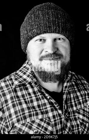 Solid bearded man in a wool cap portrait on black background Stock Photo