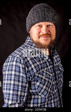 Solid bearded man in a wool cap portrait on black background Stock Photo