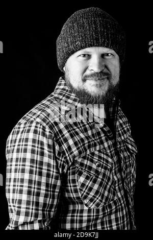 Solid bearded man in a wool cap portrait on black background Stock Photo