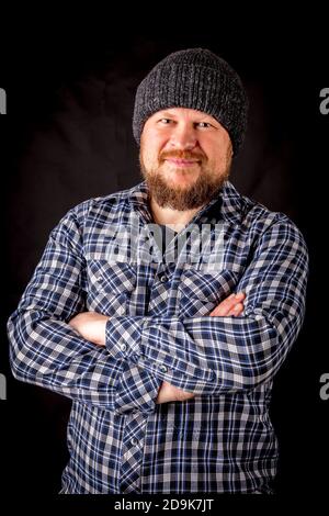 Solid bearded man in a wool cap portrait on black background Stock Photo