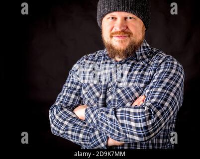 Solid bearded man in a wool cap portrait on black background Stock Photo