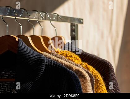 Autumn winter season knitwear.Colorful warm knitted sweaters with different knitting patterns on hanger open clothes rail Stock Photo