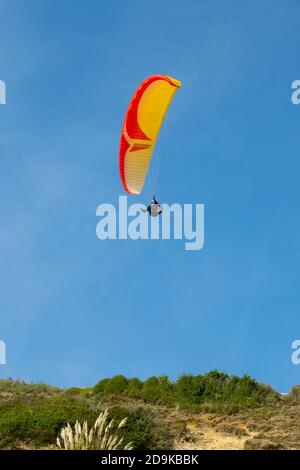 a paraglider follows the thermals along the top of the cliffs at the beach at Southbourne in Bournemouth, Dorset. 22 September 2014. Photo: Neil Turner Stock Photo