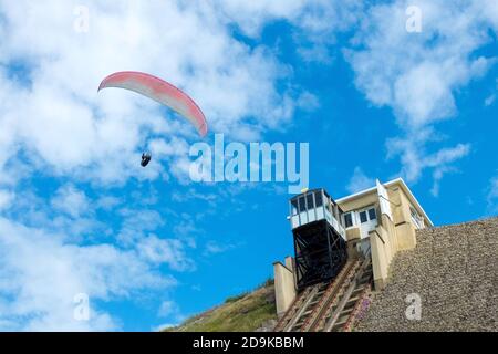 a paraglider follows the thermals past the cliff lift along the top of the cliffs at the beach at Southbourne in Bournemouth, Dorset. 08 June 2014. Photo: Neil Turner Stock Photo