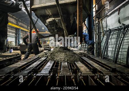 The production process is the creation of reinforced concrete pillars. An industrial worker at the plant is engaged in the manufacture of reinforced c Stock Photo