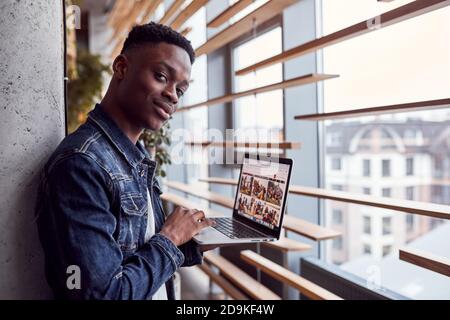 Young positive african american guy standing indoors with laptop in hands Stock Photo