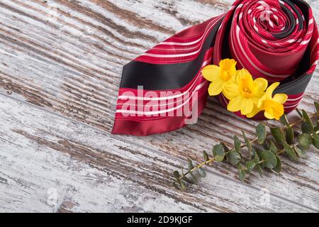 Rolled red tie with yellow flowers. Stock Photo