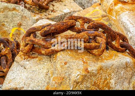 Old rusty anchor chain on a rock. Stock Photo
