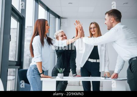 Group of young business people giving high five to each other in the office Stock Photo