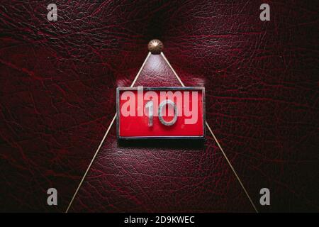 Closeup shot of the number 10 in a red square on a leather surface Stock Photo