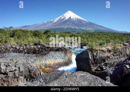 Osorno Volcano view from Petrohue Waterfalls viewpoint. River flowing against volcanic landscape with clear blue sky. Chile Stock Photo