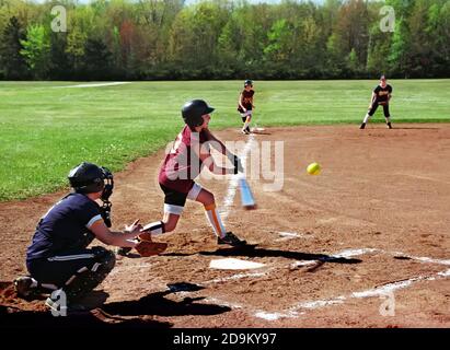 Female hits softball during baseball game Stock Photo