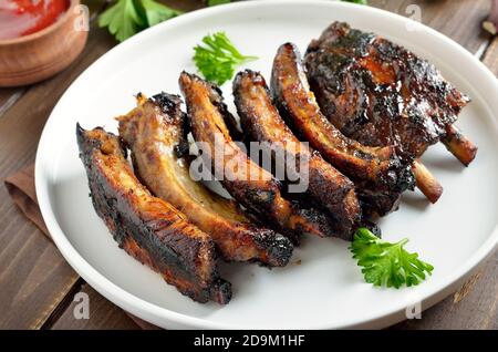 Grilled pork ribs on white plate, close up view.  Tasty bbq meat Stock Photo