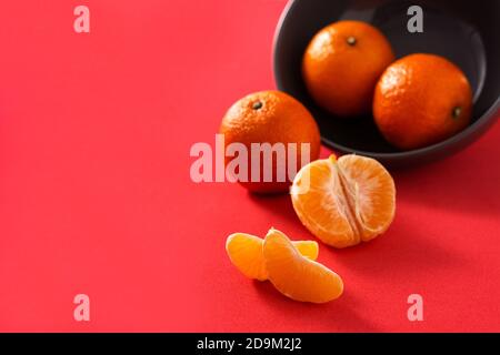 Fresh tangerines in bowl on red background Stock Photo