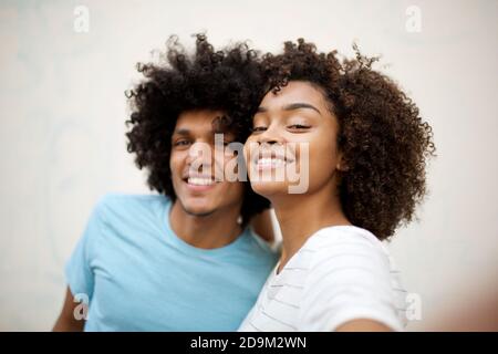 Close up portrait happy young  man and woman with afro hair taking selfie against white background Stock Photo