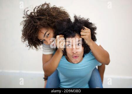 Portrait happy young couple with young man giving piggyback ride to african american woman Stock Photo