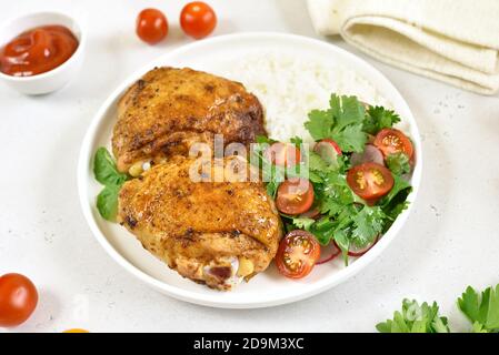 Fried chicken thighs with vegetables in plate on white stone background Stock Photo