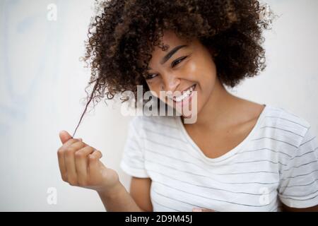 Close up portrait happy young african american woman pulling curly hair Stock Photo