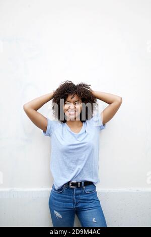 Portrait happy young african american woman with hands behind head against white background Stock Photo