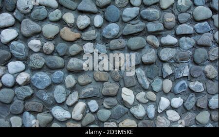 Stone wall texture, road made of small round and sea stones Stock Photo