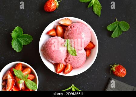 Strawberry ice cream in bowl on dark stone background. Top view, flat lay Stock Photo