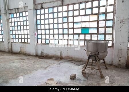 Square windows and a kettle inside an old abandoned industrial building Stock Photo