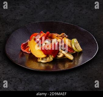 Assorted farm fresh roast vegetables on black plate, dark background Stock Photo