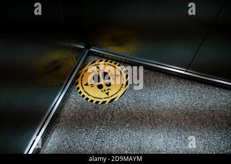 Yellow warning mark on the floor in an elevator. Protecting guests from coronavirus spreading in a hotel. Social distancing during global pandemic. Stock Photo