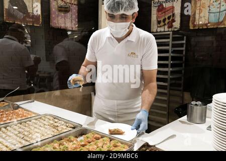 Belek, Turkey - October 2020: Hotel staff in gloves, masksserving food at сanteen in an all-inclusive resort in Antalya. Healthy safety measures Stock Photo