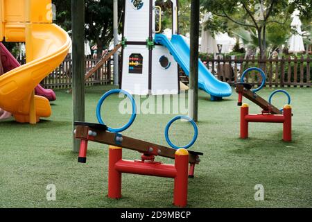 Empty swings on kindergarten playground. Unattended slide and swing set during coronavirus outbreak. Closed for children in pandemic. Nobody playing Stock Photo