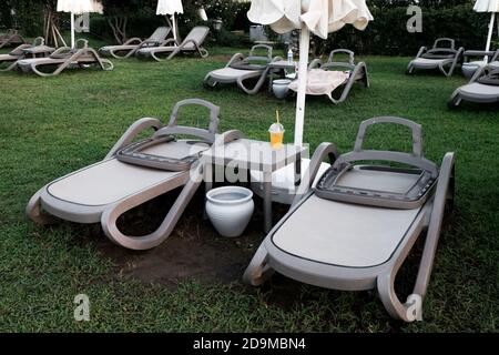 Belek, Turkey - October 2020: Empty sunbeds on grass in daylight. No people around in a luxury resort. Deserted place during global pandemic. Stock Photo