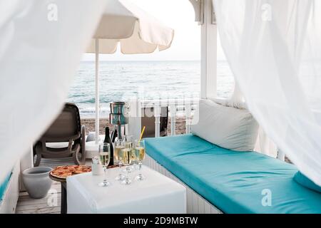 Belek, Turkey - October 2020: Luxury VIP lounge with curtains and beds on the beach near Mediterranean sea. Champagne and pizza near sunbeds, sea Stock Photo