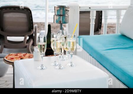 Luxury VIP lounge for rich tourists on a beach near Mediterranean sea. Champagne and pizza near sunbeds, sea in background. Romantic summer getaway Stock Photo