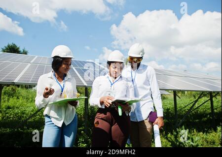 African american technician checks the maintenance of the solar panels. Group of three black engineers meeting at solar station. Stock Photo