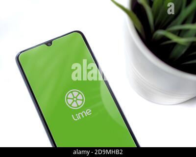 Lod, Israel - July 8, 2020: Modern minimalist office workspace with black mobile smartphone with Lime app launch screen with logo on white background. Stock Photo