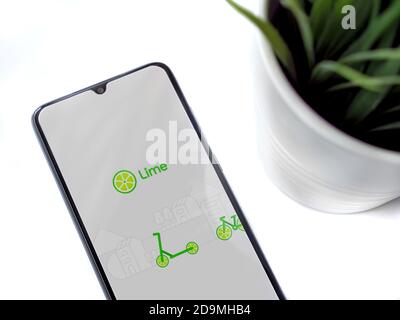 Lod, Israel - July 8, 2020: Modern minimalist office workspace with black mobile smartphone with Lime app launch screen with logo on white background. Stock Photo