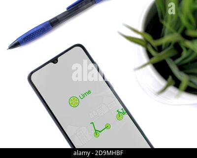 Lod, Israel - July 8, 2020: Modern minimalist office workspace with black mobile smartphone with Lime app launch screen with logo on white background. Stock Photo