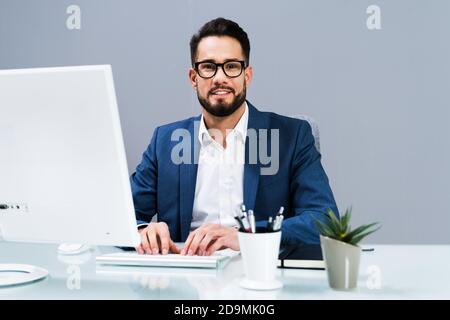 Smiling Business Man Working On Business Computer At Desk Stock Photo