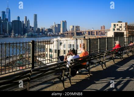 New York City, New York, United States of America - People on Brooklyn Heights waterfront, looking towards Manhattan skyline and Brooklyn Bridge, USA. Stock Photo