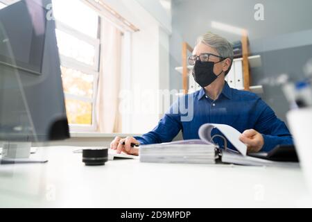 Senior Accountant Man Working With Invoice In Face Mask Stock Photo