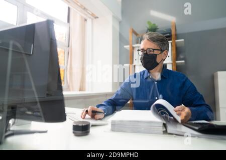 Senior Accountant Man Working With Invoice In Face Mask Stock Photo