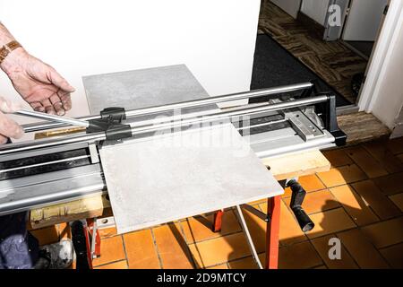 the mason cuts a ceramic tile with a tile cutter Stock Photo