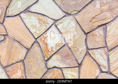 Close-up of a wall tiled with sandstone tiles. Design, construction. Chaotic stone mosaic. Natural stone. A versatile background for different purpose Stock Photo