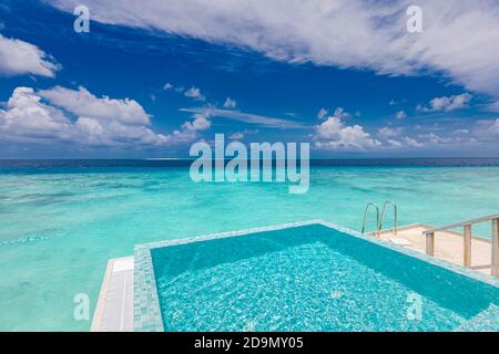 Infinity swimming pool with sea and ocean view on blue sky background. Luxury infinity pool over amazing turquoise lagoon and ladder into the water Stock Photo